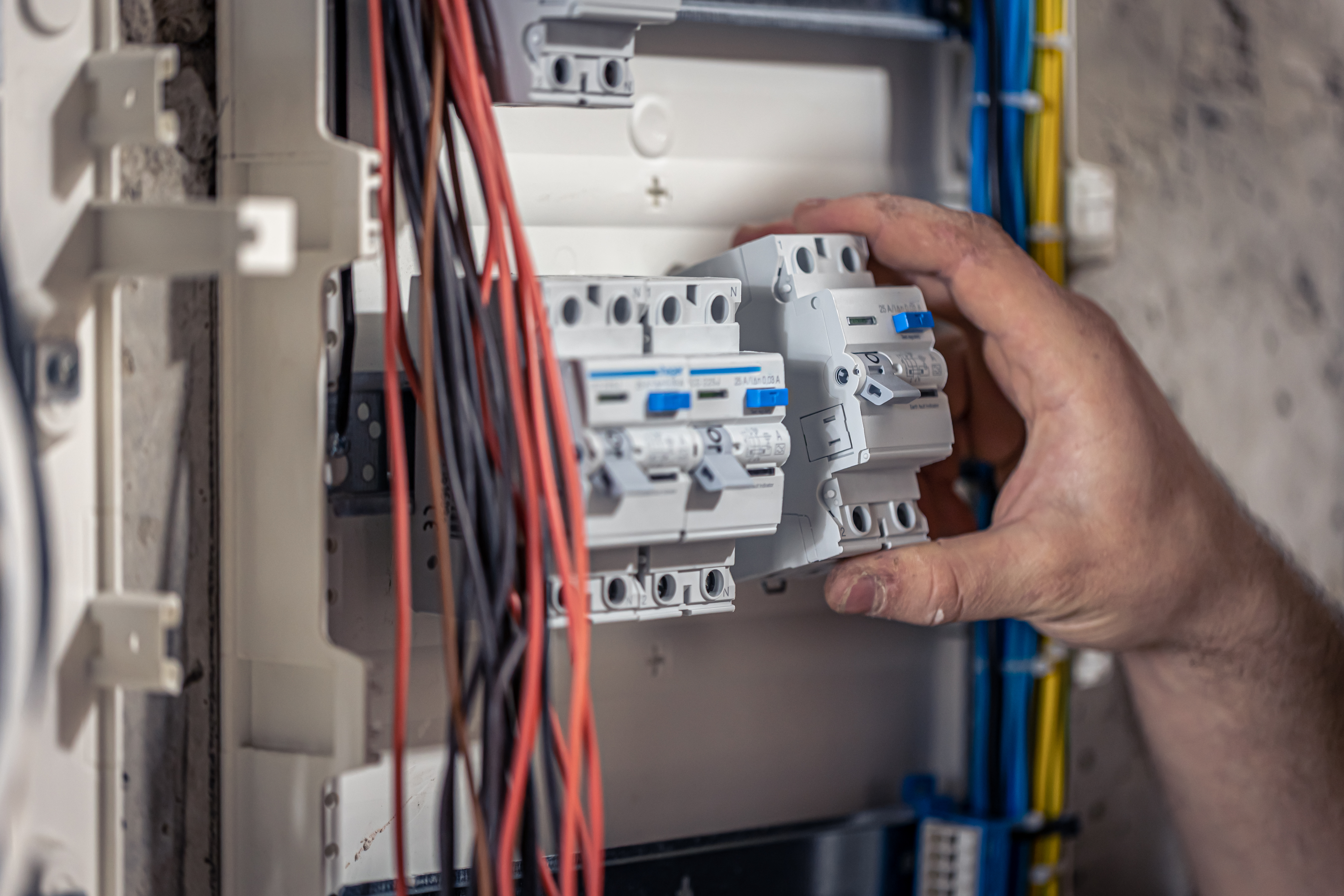 male-electrician-works-in-switchboard-with-an-electrical-connecting-cable